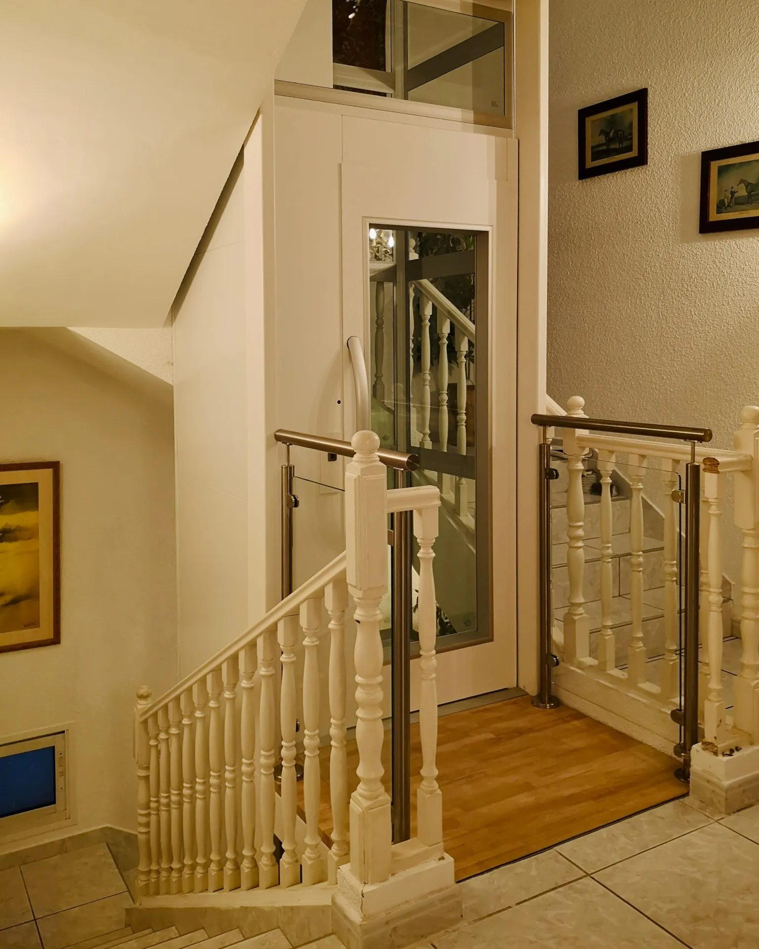 Ascenseur privatif blanc intégré dans une cage d'escalier traditionnelle